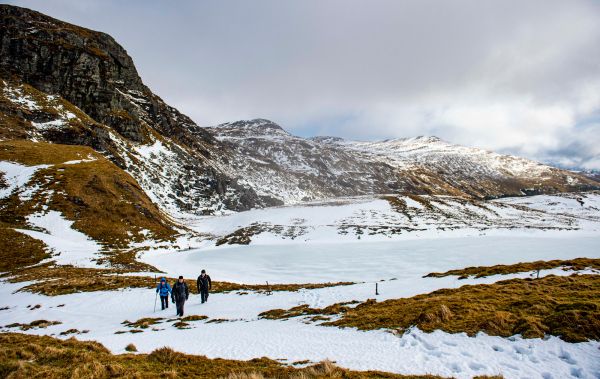 Two walkers dwarfed by snow covered mountains and terrain