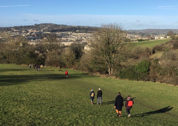 walkers walking down a hill towards the city of Bath.