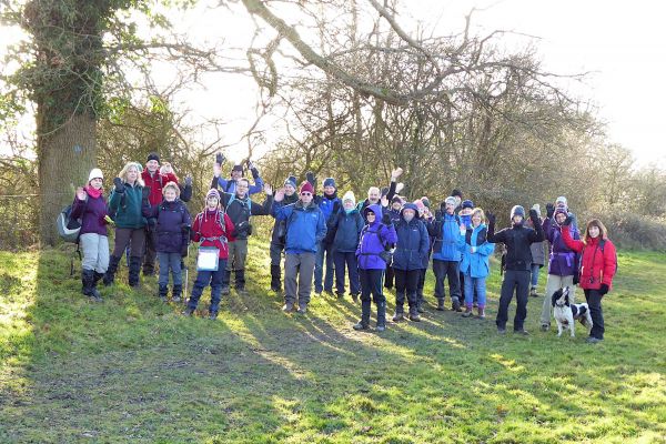 Waving walkers underneath a tree in bright sunshine.