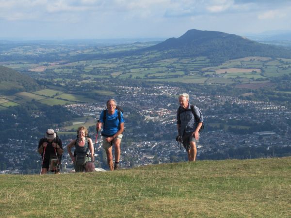 Walkers cresting a hill with views for miles in the background.