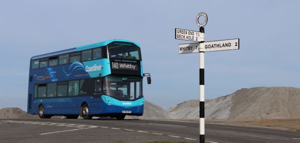 Coastliner bus passing by a road sign on a road in Yorkshire 