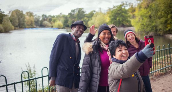 A group of walkers standing in front of a lake taking a selfie