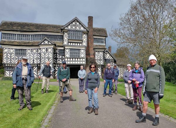 A group of walkers outside a tudor house.