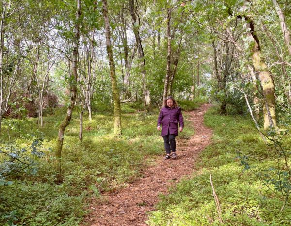 A female walker on downhill path in Corpach woods