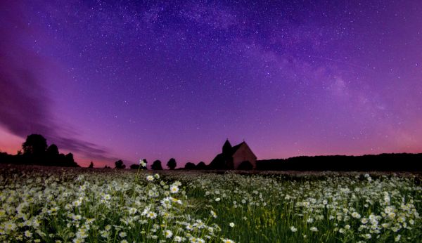 A rural cottage being lit up by the Northern Lights.