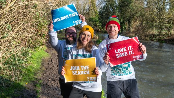 three don't lose your way volunteers stand by a river showing signs supporting the campaign