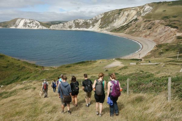 Walkers going downhill towards a wide cove.