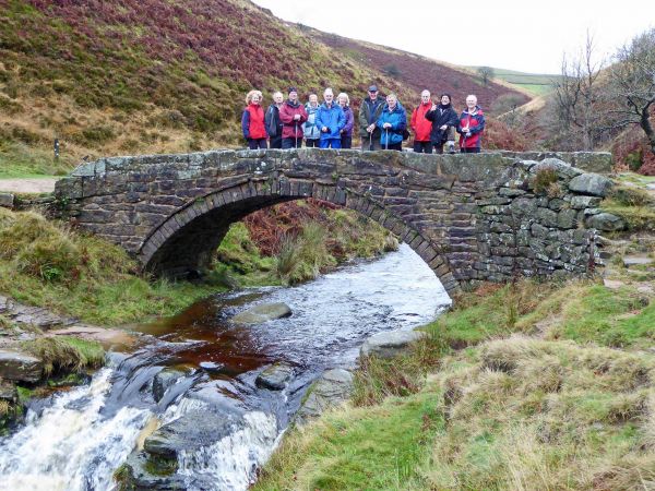 walkers going over a small stone bridge. 