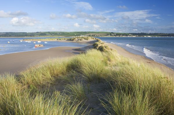 A thin, grassy sand dune runs along the centre of a small island, just offshore of the mainland