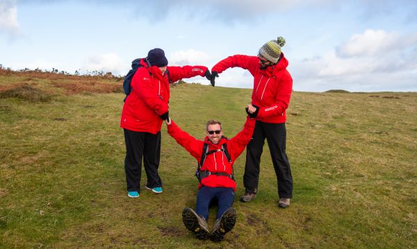 Three walkers in red jackets forming a heart shape with their arms.