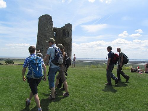 four walkers going past ruins of a castle