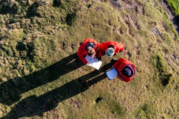 arial shot of three walkers looking at a map.