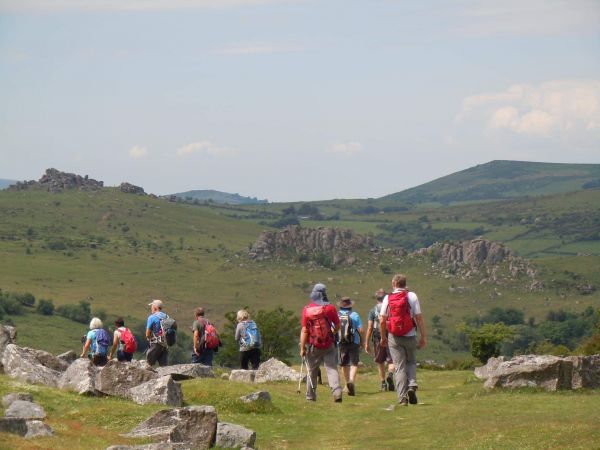 walkers on a rocky moor with hills in the background