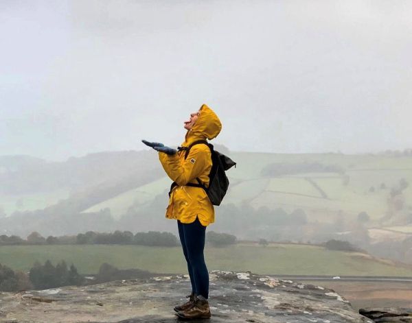 walking looking up to the sky dressed in walking boots, waterproof jacket and backpack