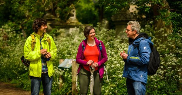 Three walkers deep in conversation with greenery in the background