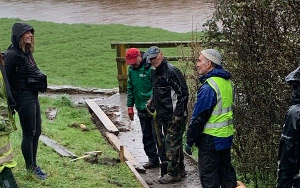 Four volunteers repairing a path in the wet weather.