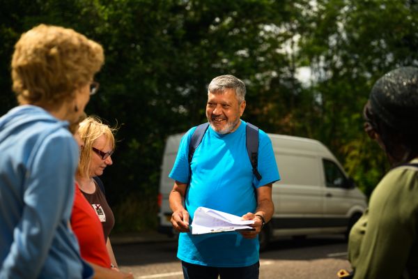 Man smiling with a clipboard, in front of a group of walkers. 