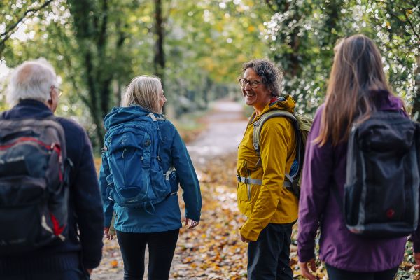 Women looking back to camera and smiling, while on group walk in the woods. 