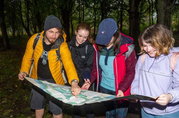 Four young ramblers looking over a map in a forest.