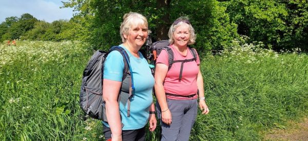 Two female walkers with backpacks on, smiling into the camera. 