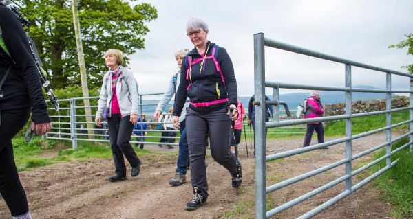 Several walkers heading through a farm gate in Scotland.