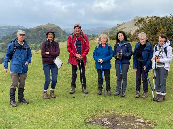 seven smiling walkers on top of a hill