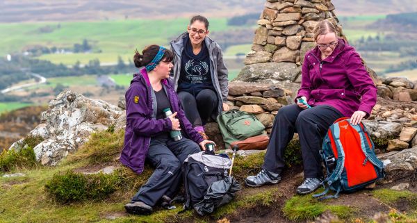 three walkers taking a break wearing waterproof jackets and equipped with backpacks 