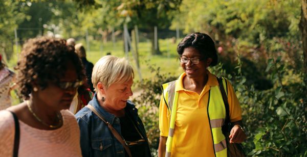 A walk leader smiling as two walkers pass her.