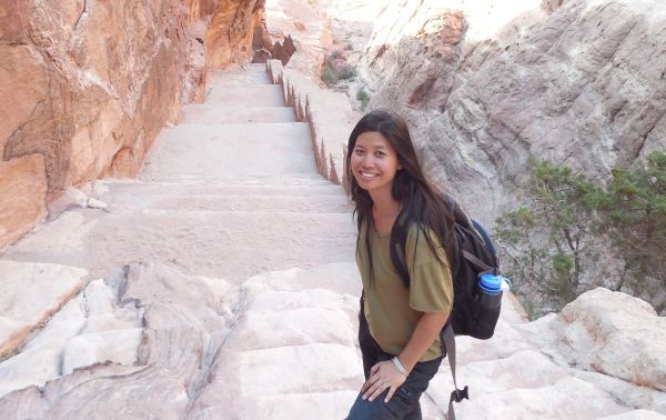 A female traveller with a backpack standing on steep steps in Petra, Jordan