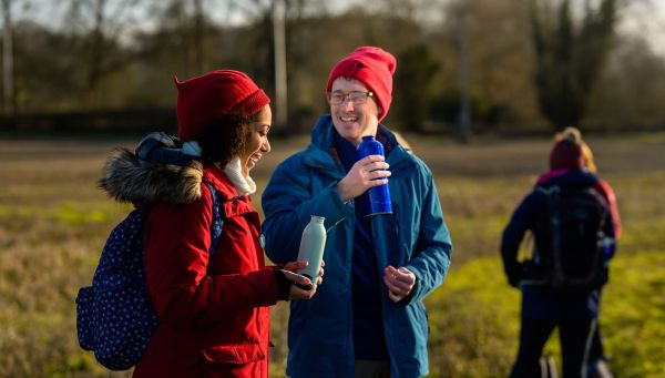 Two walkers having a conversation whilst drinking out of flasks.