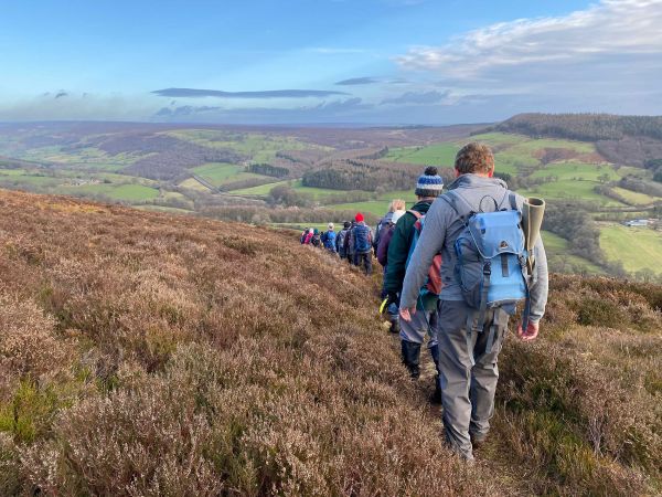 walkers on top of heather-covered hill