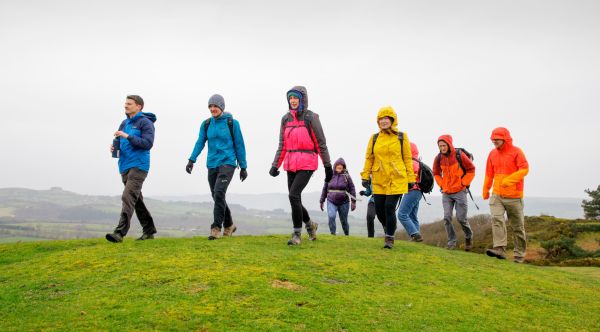 A group of walkers on a hilltop on a grey day all wearing rain jackets