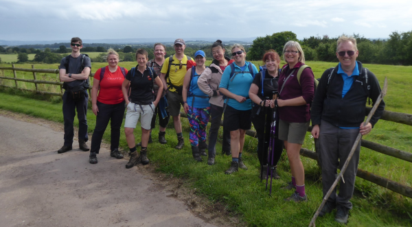 A group of walkers standing in front of a fenced field, looking into the camera 