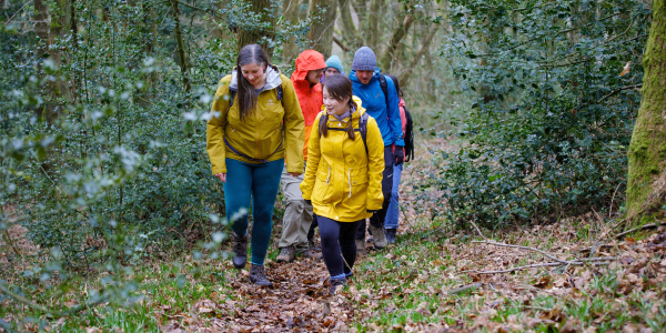 A Ramblers group wearing bright waterproof jackets walk along a path